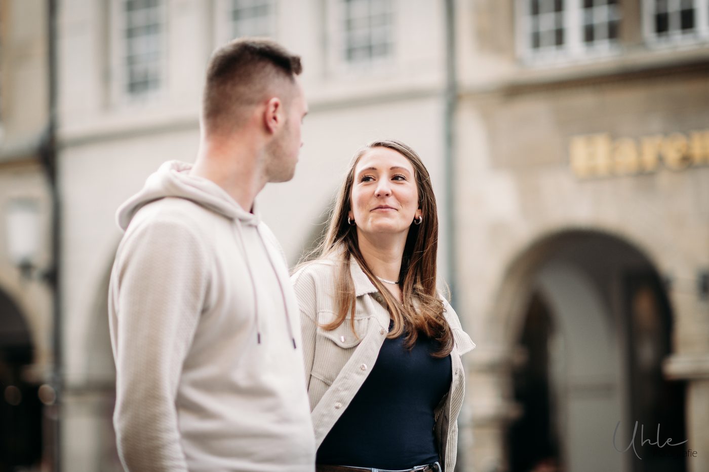 Frau blickt lächelnd zu ihrem Partner vor historischer Architektur